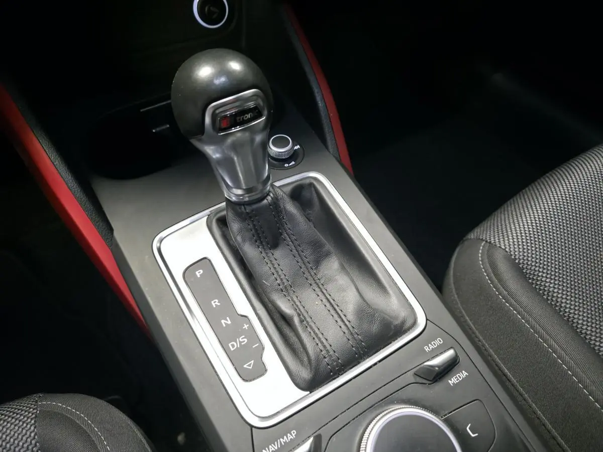 Le levier de vitesses automatique S tronic de l'Audi Q2 1.4 TFSI Sport avec garnitures intérieures rouges visibles.