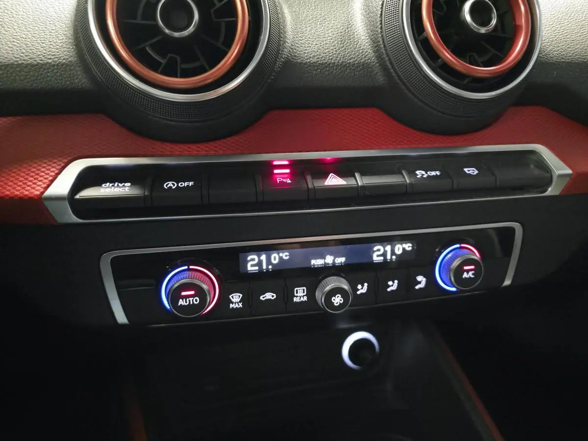 Détail du tableau de bord de l'Audi Q2 2017 avec commandes de climatisation et décorations rouges intérieures.