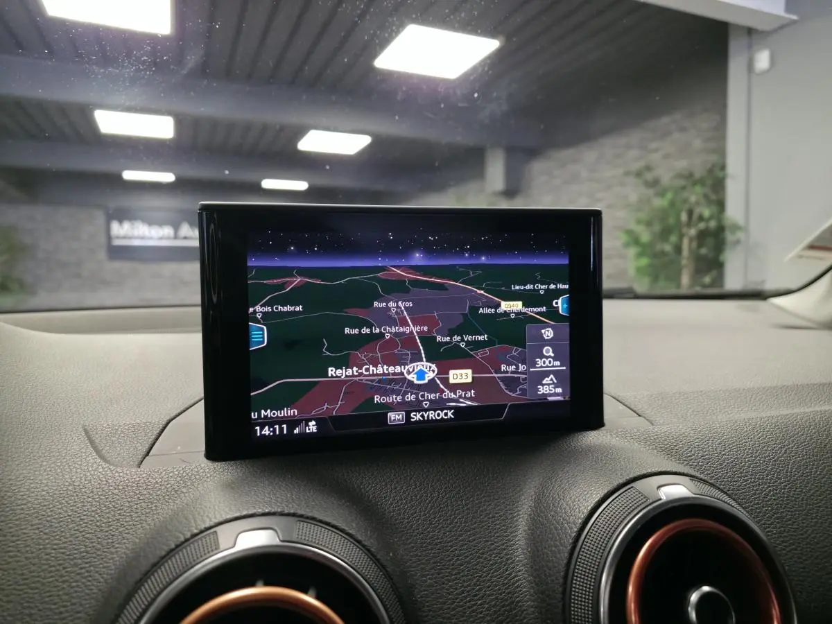 Écran de navigation MMI central dans l'habitacle d'Audi Q2 noir, avec détails de carte et ventilation rouge.