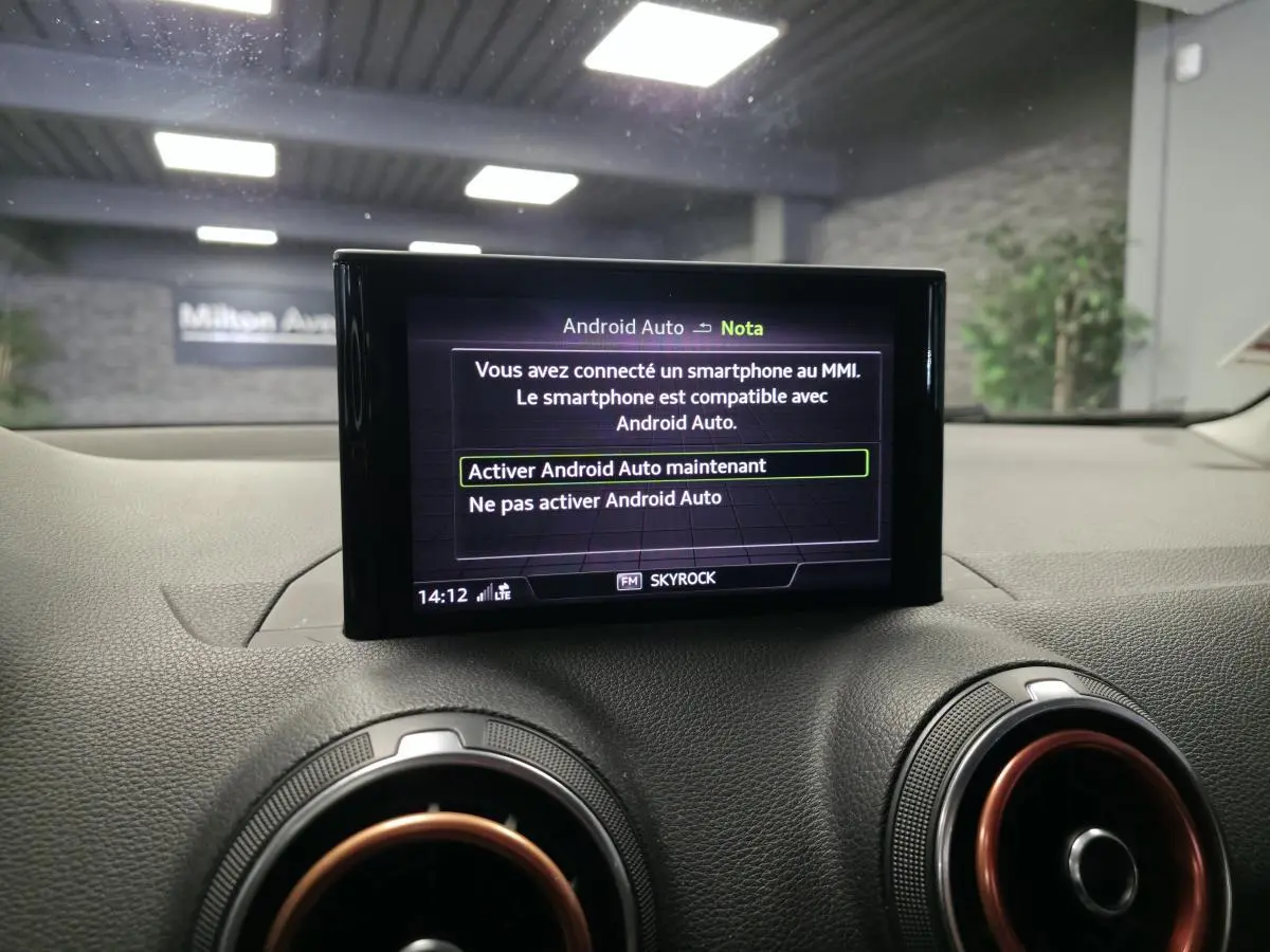 Écran central du système MMI affichant l'activation d'Android Auto, avec aérateurs ronds à décor rouge dans un Audi Q2 noir.