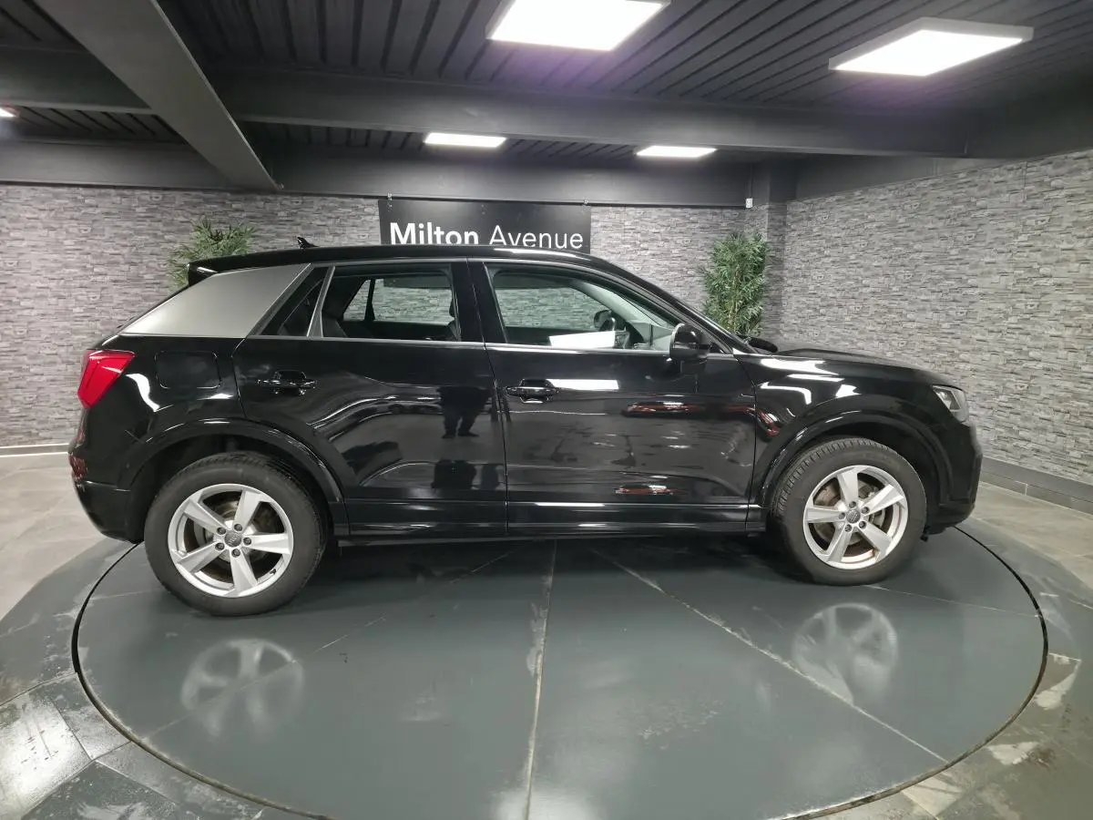 Audi Q2 noir vue de profil côté gauche dans un showroom avec jantes 5 branches et toit noir brillant.