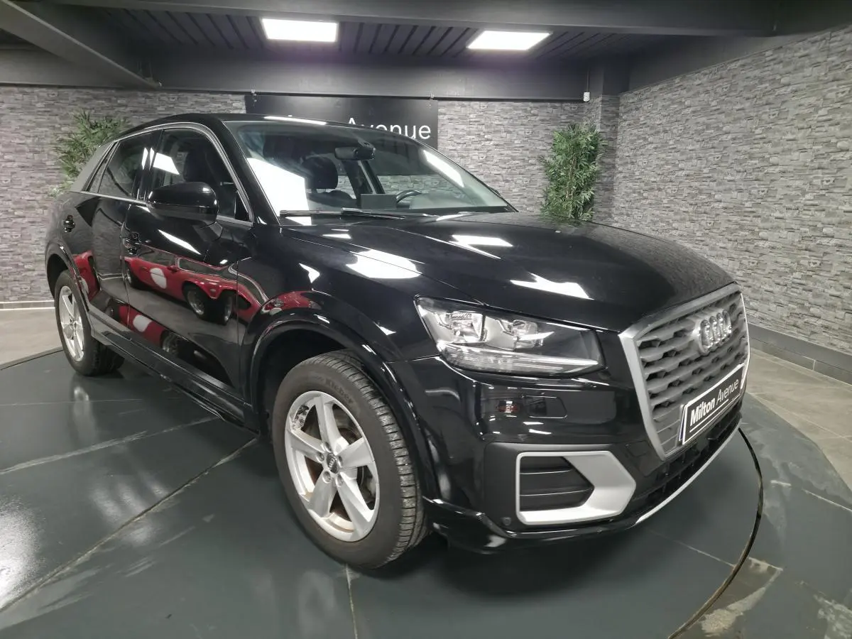 Audi Q2 noire vue en 3/4 avant droit, avec calandre grise et jantes aluminium 5 branches en étoile.