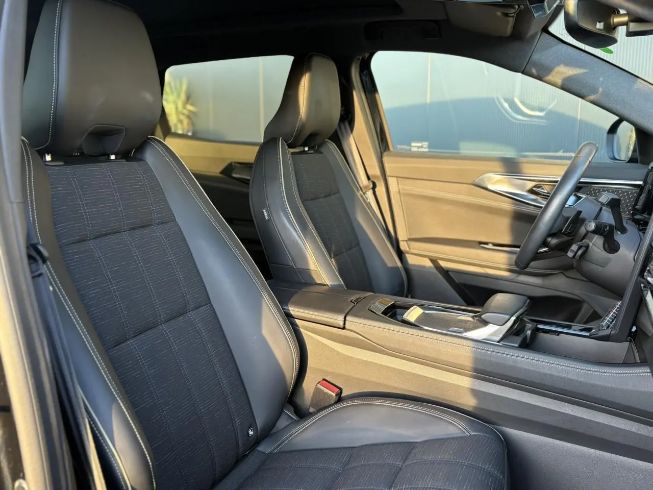 Vue intérieure côté droit du Renault Austral 2023 avec sièges mixtes similicuir et tissu carbone foncé aux surpiqûres or.