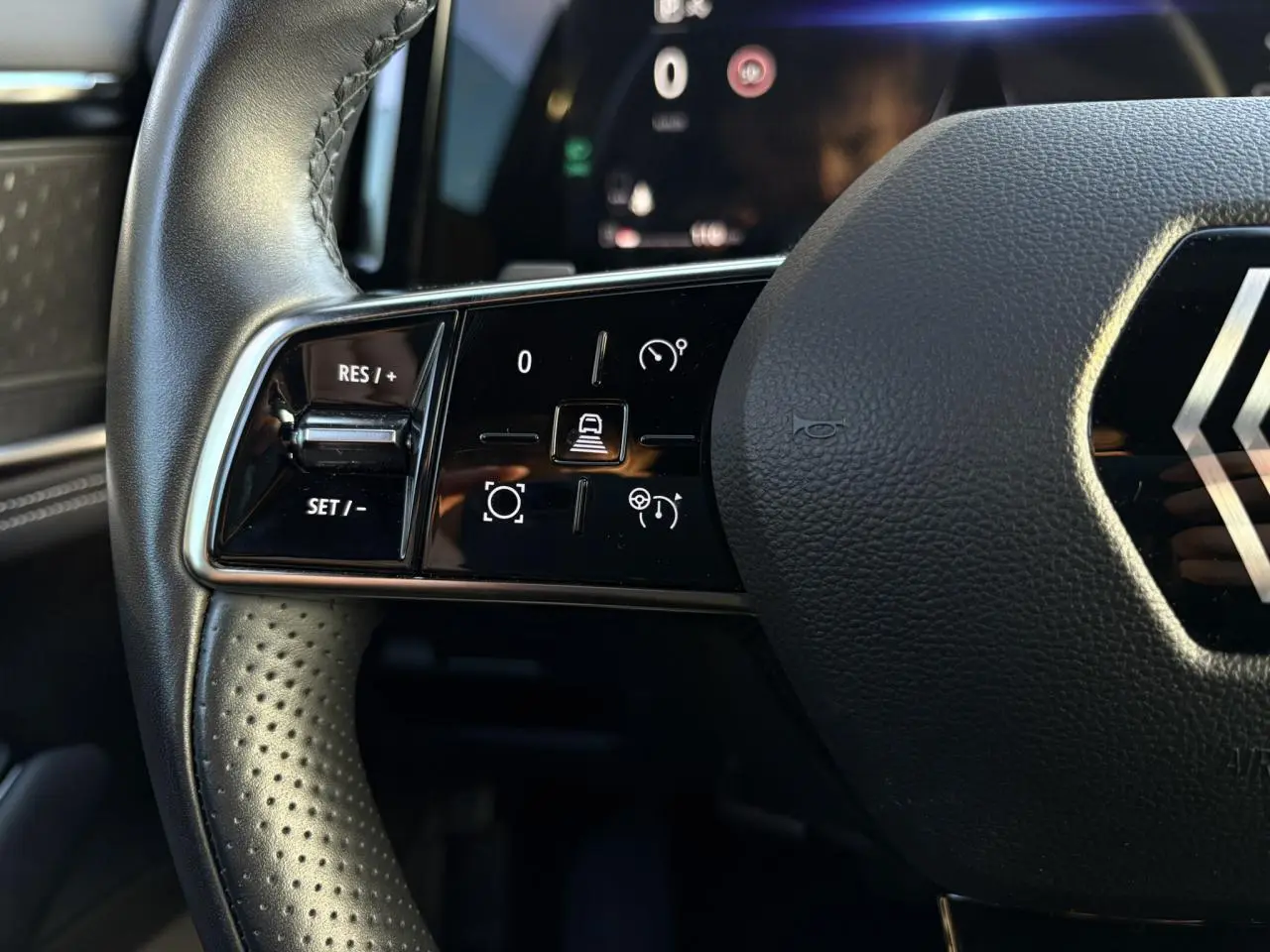 Gros plan sur la partie gauche du volant cuir perforé du Renault Austral 2023 avec commandes de régulateur adaptatif.