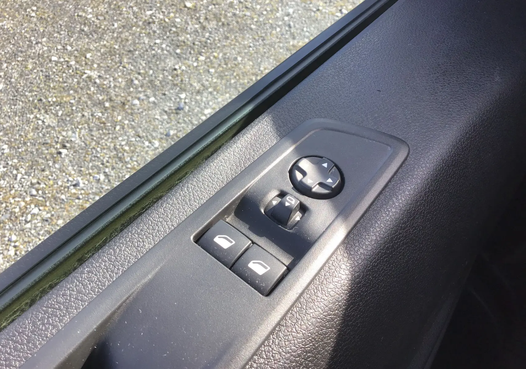 Gros plan sur les commandes de lève-vitres et réglage des rétroviseurs côté conducteur du FIAT Scudo Fourgon blanc 2024.