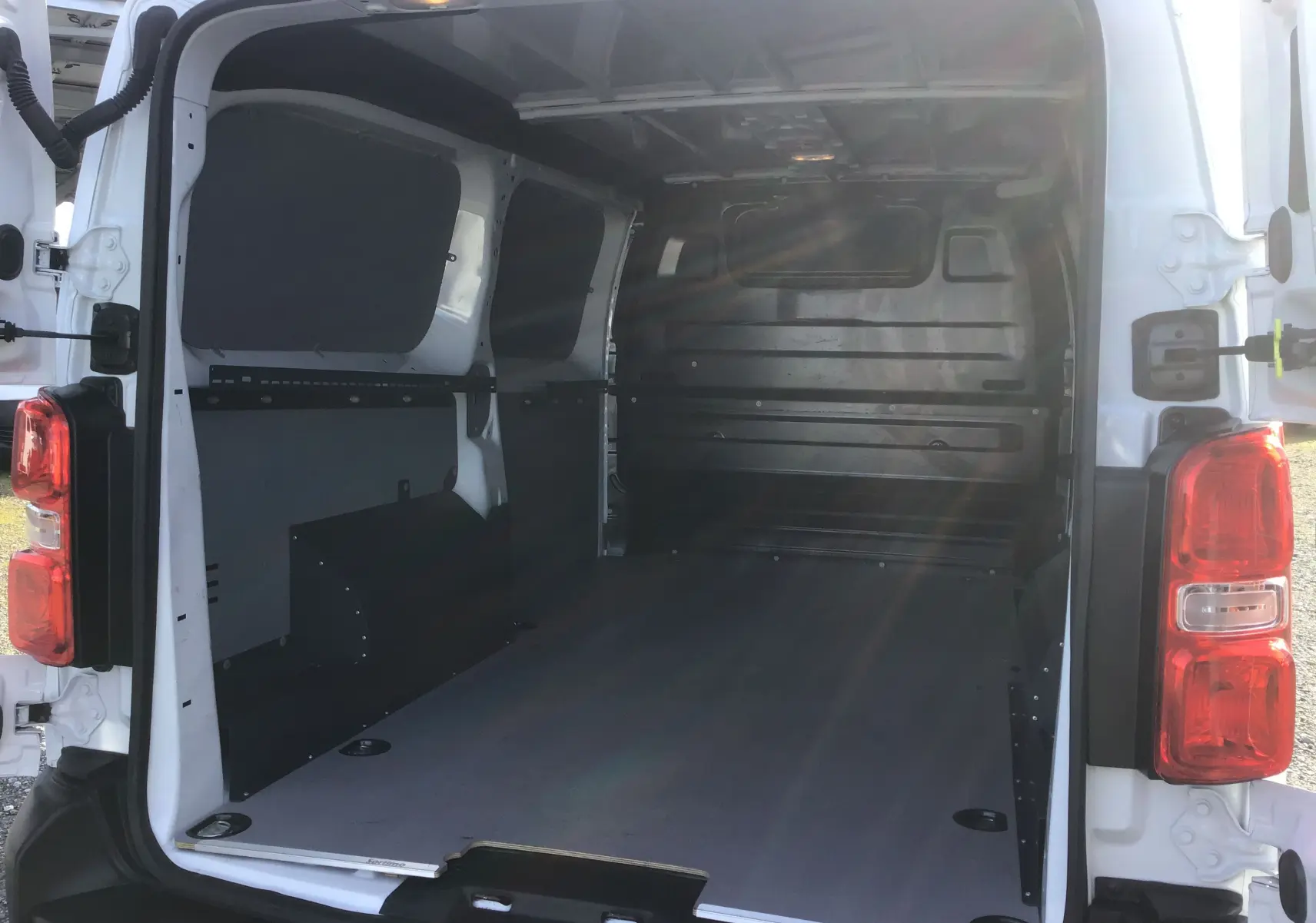 Vue arrière ouverte du FIAT Scudo Fourgon blanc 2024, montrant l’espace de chargement vide avec protections intérieures noires.