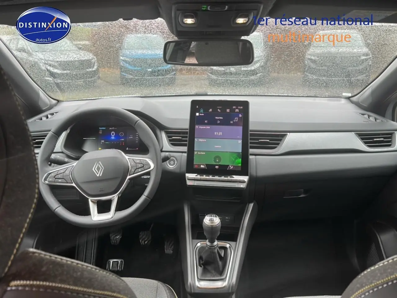 Vue intérieure avant du Renault Captur gris rafale 2025, volant multifonction et écran tactile central vertical.