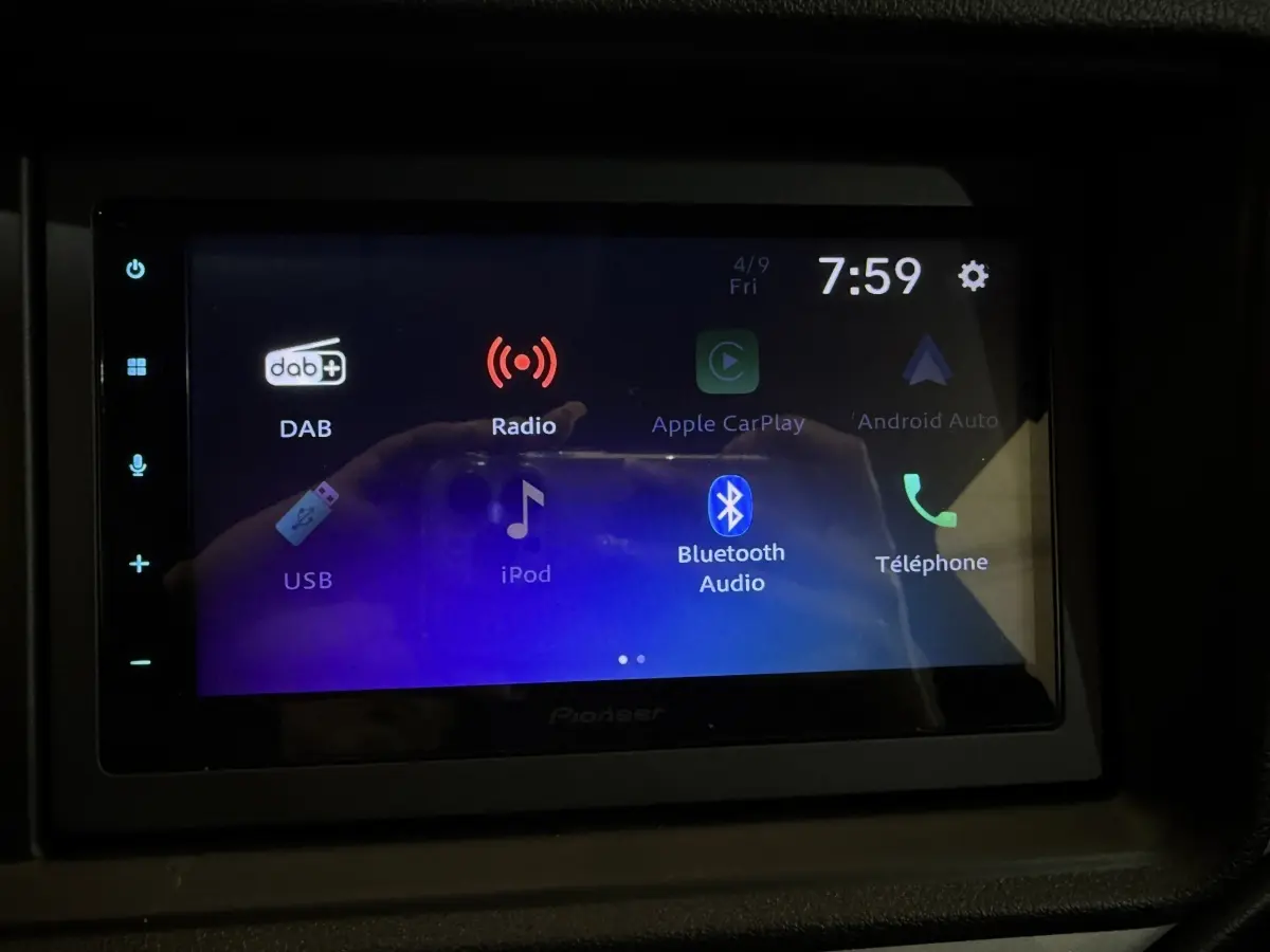 Écran tactile multimédia allumé dans l'habitacle de l'AIXAM AMBITION 0.5 CROSSOVER PREMIUM gris foncé, vue frontale.