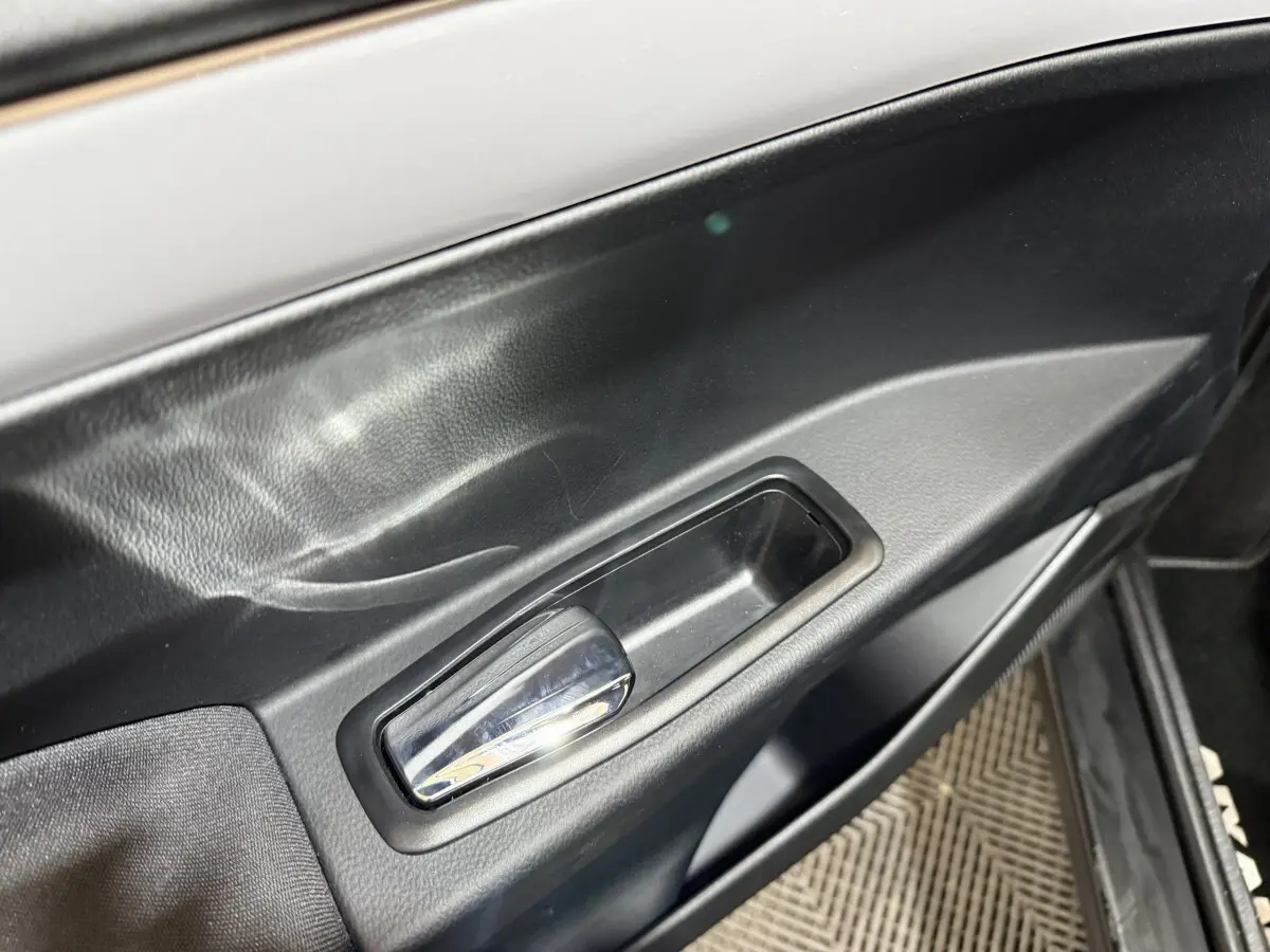 Détail de la poignée de porte intérieure noire de l'AIXAM AMBITION 0.5 CROSSOVER PREMIUM 2026, côté conducteur.