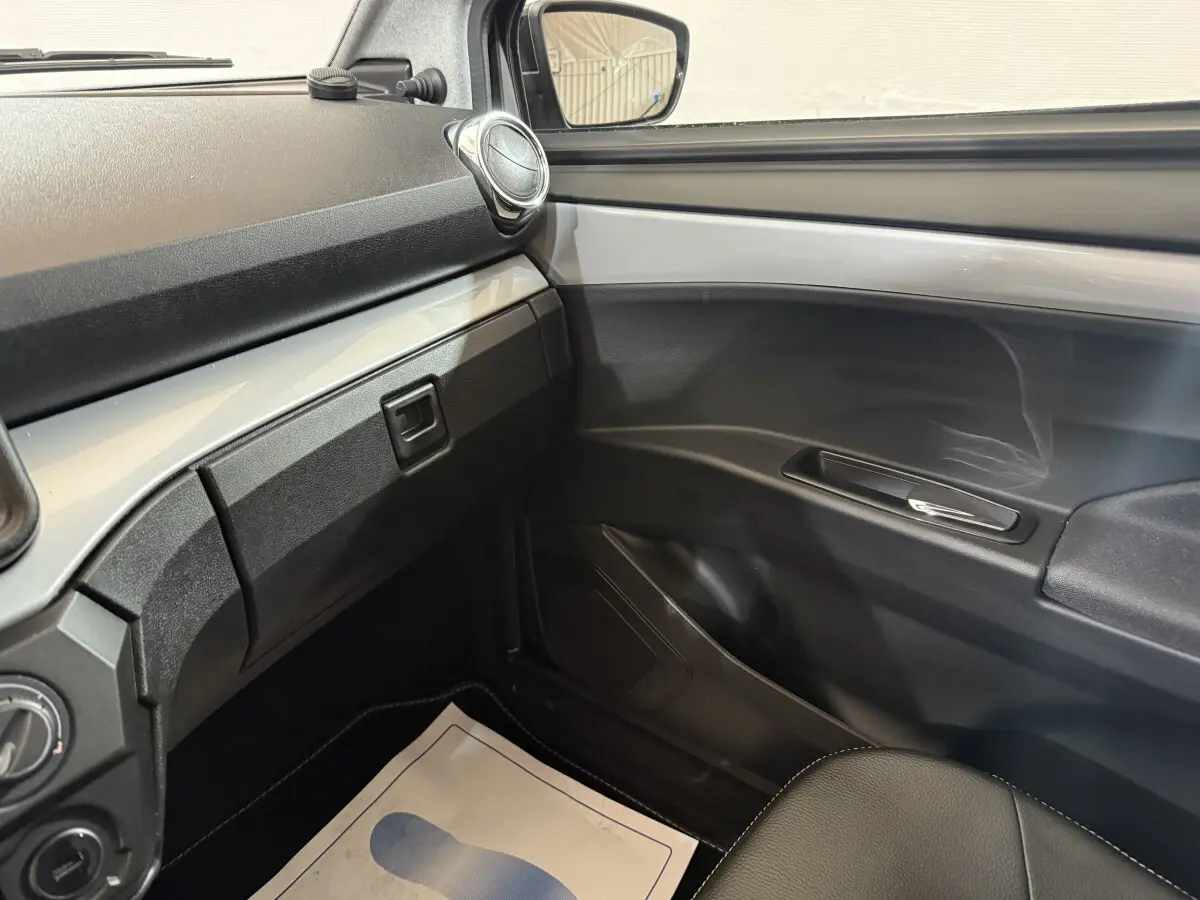 Vue intérieure côté passager de l’AIXAM AMBITION 0.5 CROSSOVER PREMIUM 2026, tableau de bord et porte gris foncé.