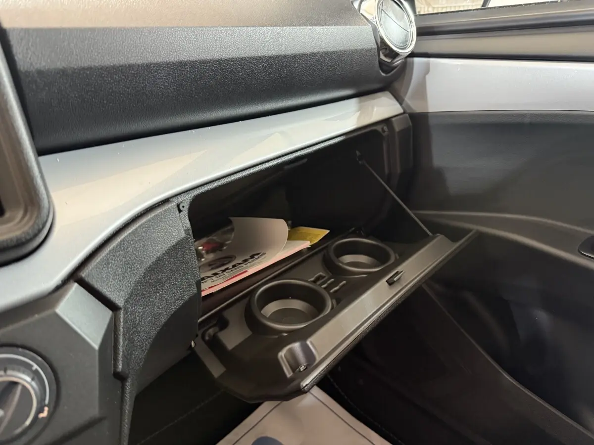 Intérieur côté passager de l'AIXAM Ambition 0.5 Crossover Premium 2026 gris foncé, boîte à gants ouverte avec porte-gobelets.