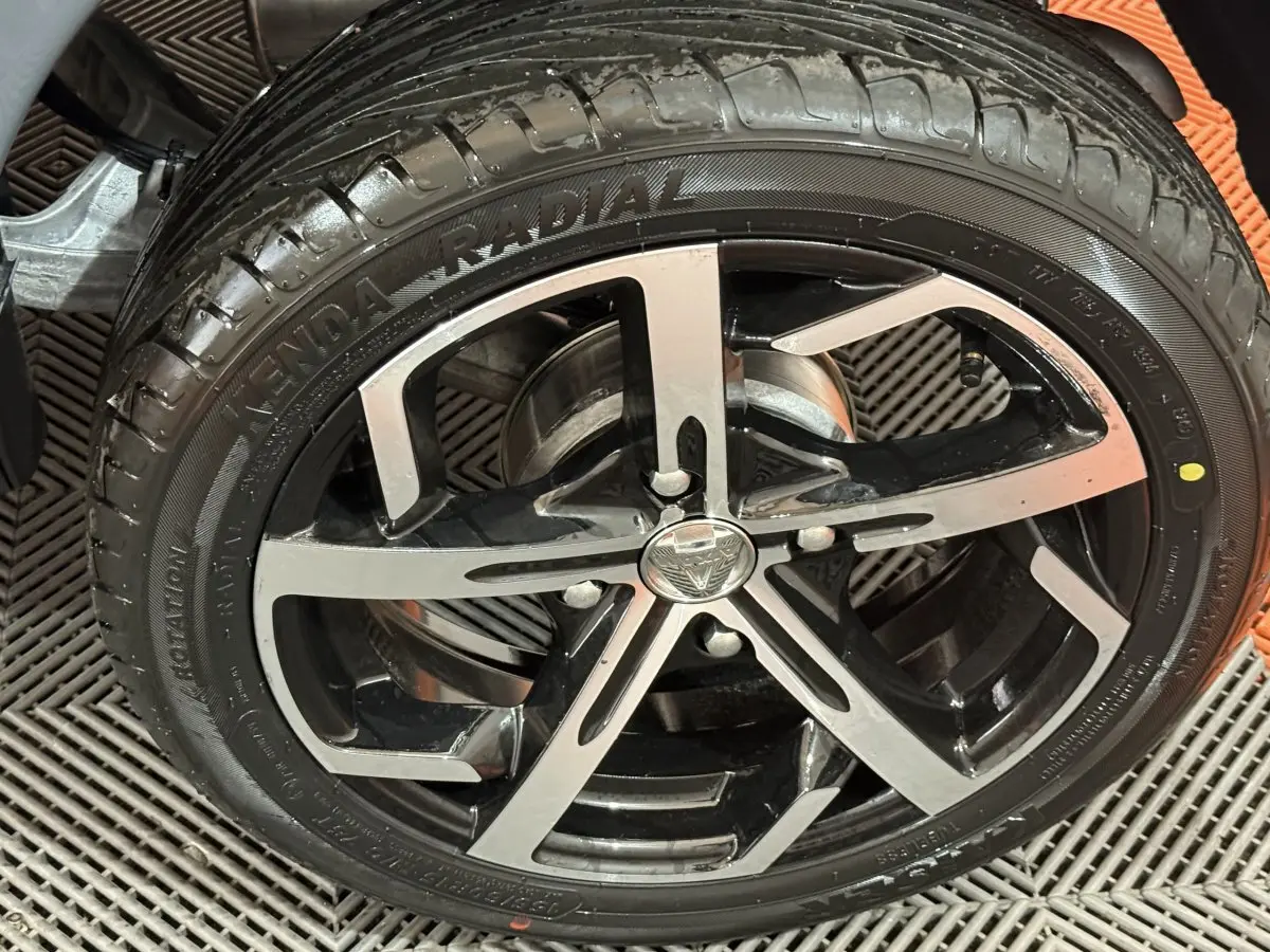 Gros plan sur la jante noire et argentée d’une Aixam Ambition 0.5 Crossover Premium gris foncé, vue côté roue.