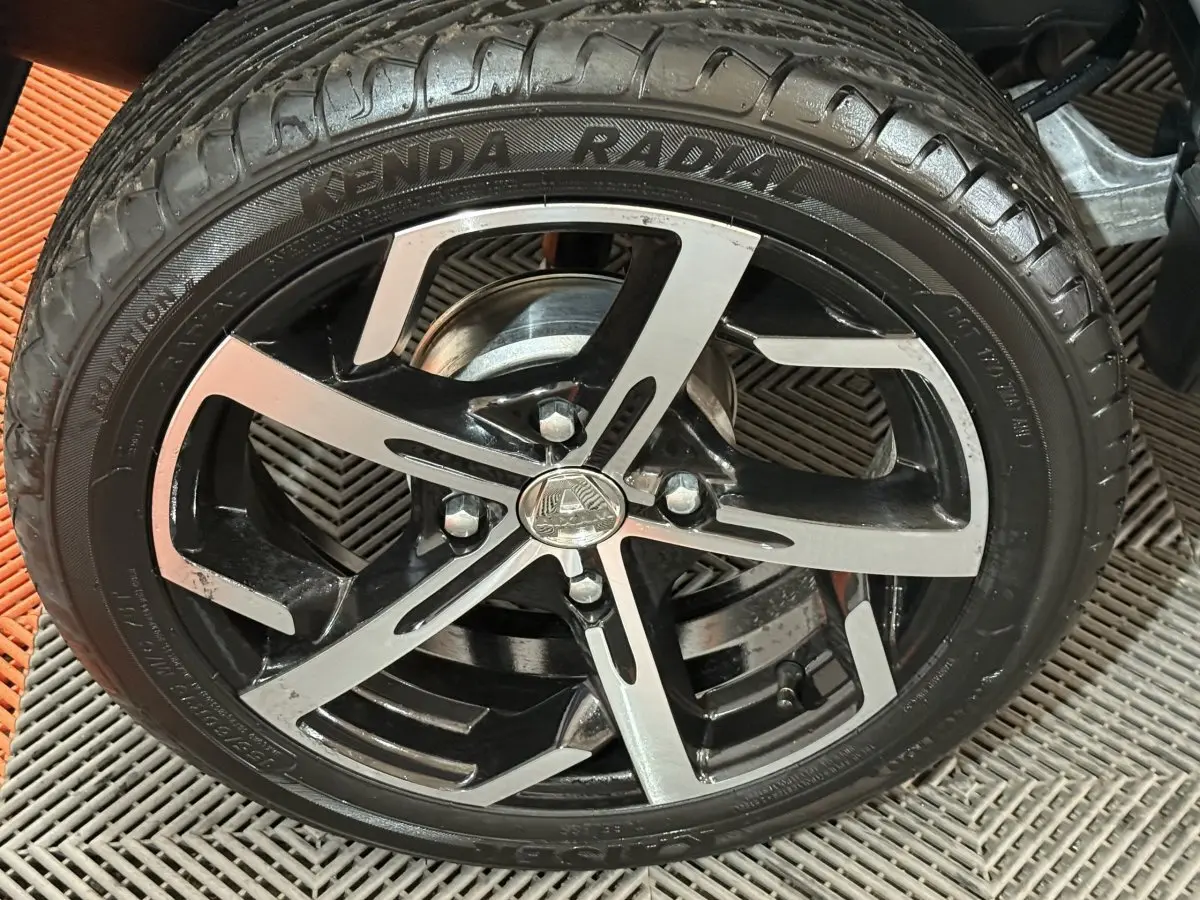 Gros plan sur la roue avant droite de l'AIXAM AMBITION 0.5 CROSSOVER PREMIUM gris foncé avec jante noire et argent.