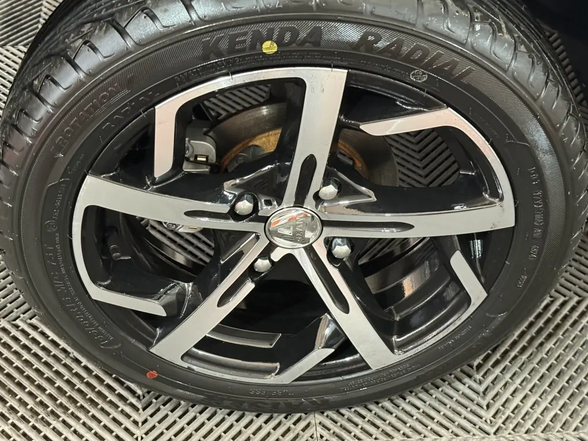 Gros plan sur la jante noire et argentée d'une Aixam Ambition 0.5 Crossover Premium gris foncé, roue avant.