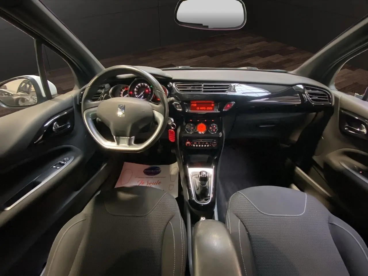 Vue intérieure avant de la Citroën DS3 1.6 e-HDI 90 AirDream So Chic, tableau de bord noir avec volant et console centrale.