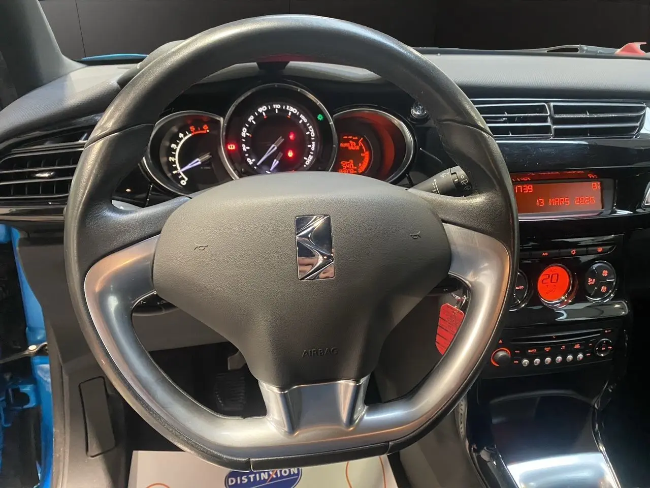 Vue intérieure centrée sur le volant et le tableau de bord noir du Citroën DS3, avec affichages numériques rouges.