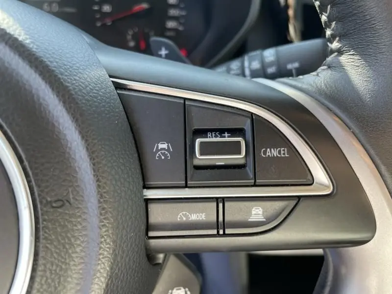 Gros plan sur les commandes de régulateur de vitesse au volant d'une Suzuki Swift 2024 bleu métal.