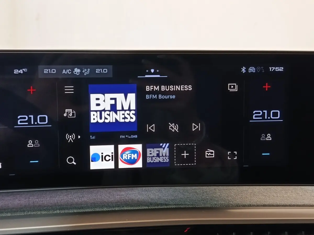 Écran tactile central du tableau de bord du Peugeot 5008 gris clair, affichant la radio BFM Business.