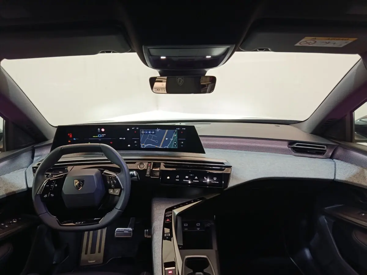 Vue intérieure avant du Peugeot 5008 gris clair 2026, tableau de bord numérique large et volant cuir multifonctions.