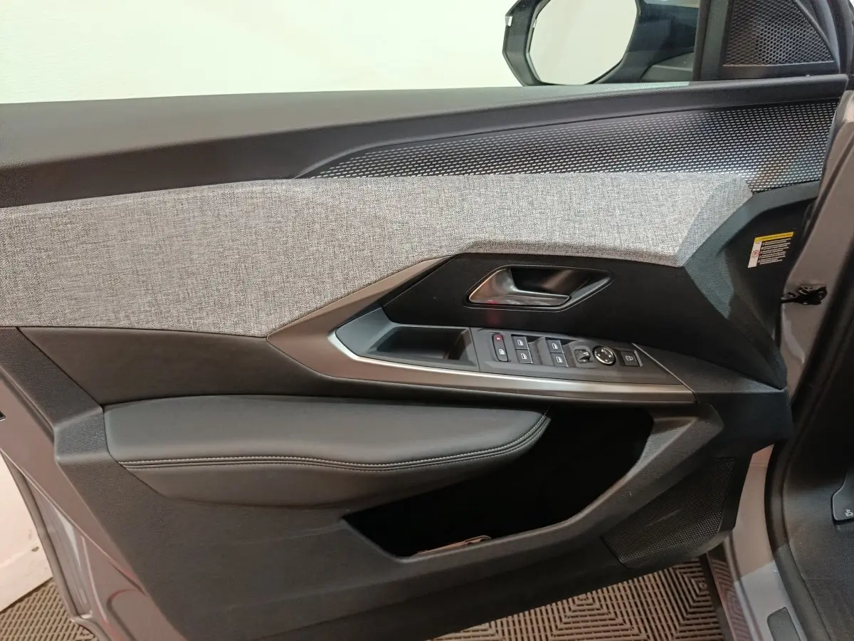 Vue intérieure côté gauche de la porte avant gris clair du Peugeot 5008 avec commandes électriques et habillage tissu et cuir.