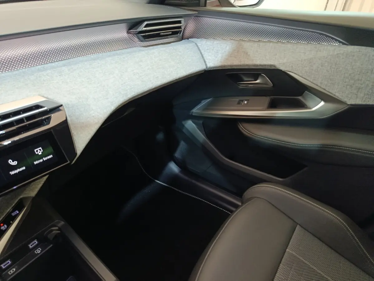 Vue intérieure côté passager du Peugeot 5008 gris clair 1.6 PHEV 195 E-DCS7 GT, avec tableau de bord et garnitures tissu clair.