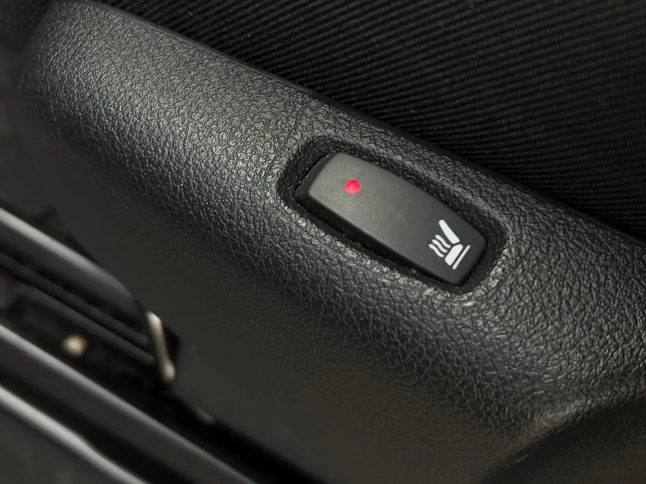 Gros plan sur le bouton de siège chauffant noir dans l'habitacle du Nissan Primastar Combi noir métal 2025