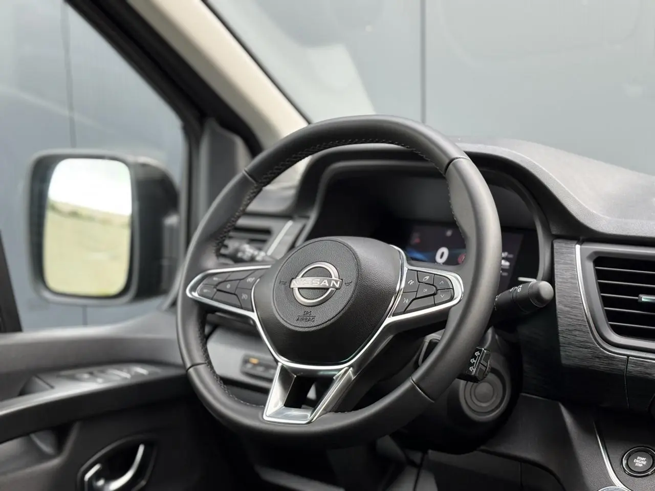 Volant Nissan noir avec commandes intégrées, tableau de bord et rétroviseur côté gauche du Primastar Combi 2025.