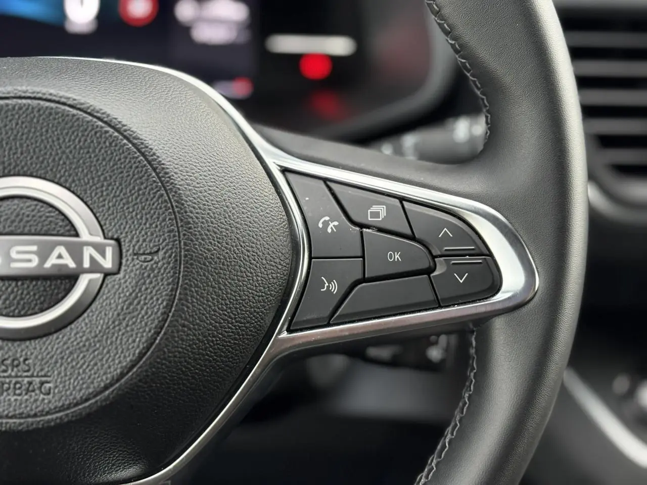 Gros plan sur les commandes multifonctions du volant noir du Nissan Primastar Combi 2025, finition Tekna.