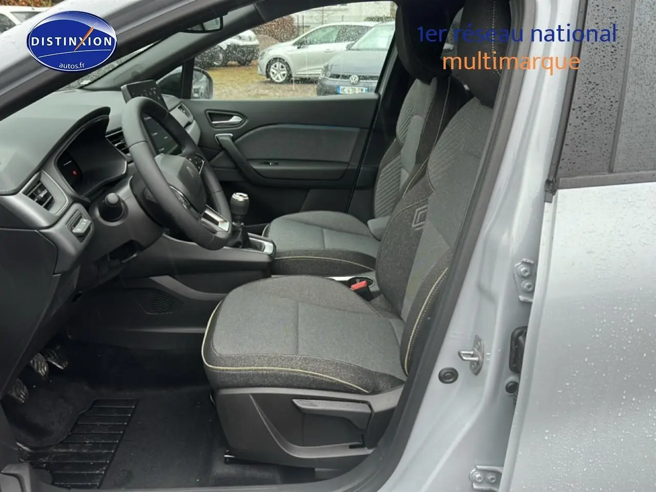 Vue intérieure côté conducteur du Renault Captur gris rafale 2025, montrant sièges tissu et volant multifonction.