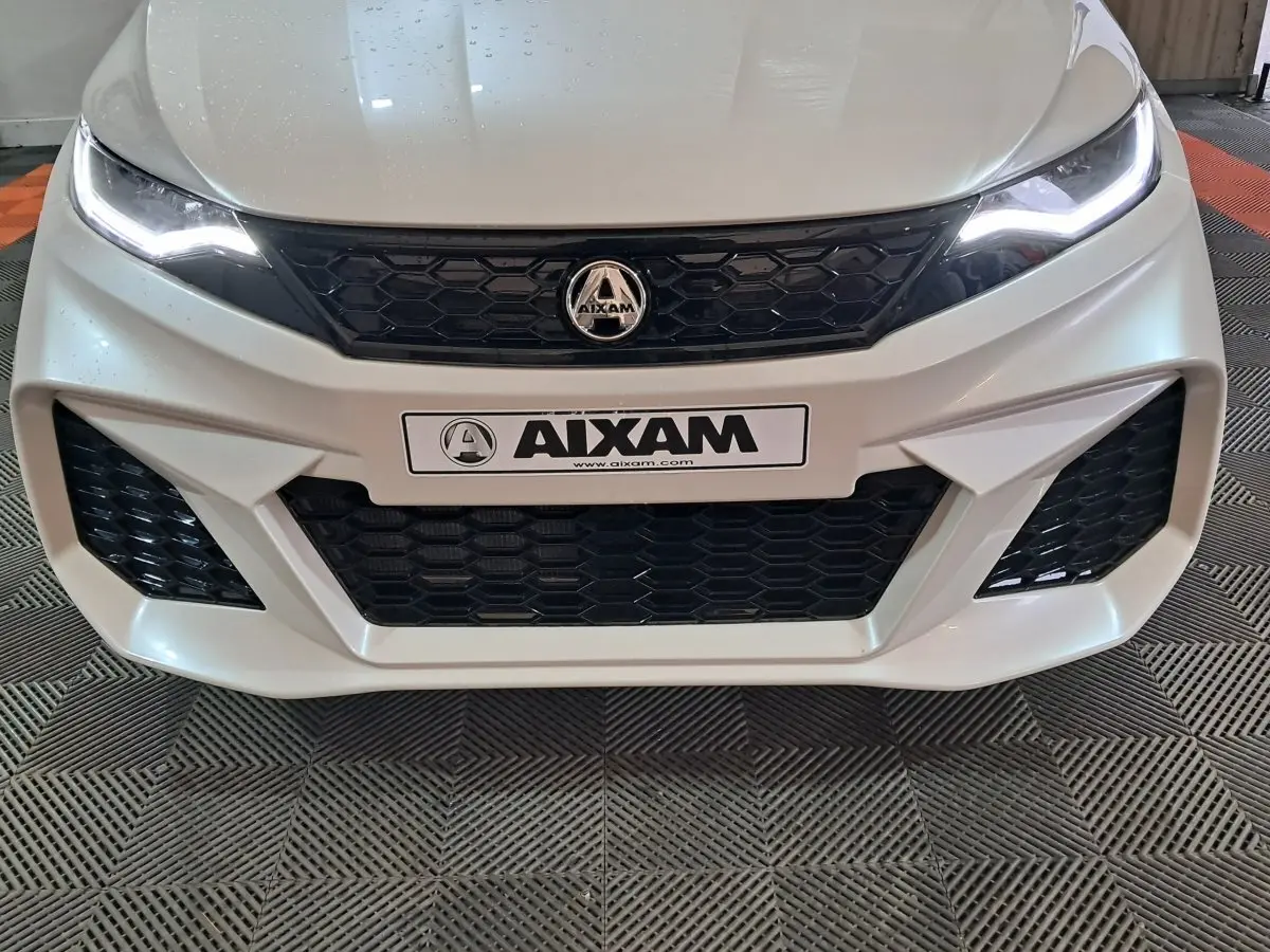 Vue frontale rapprochée de l'AIXAM AMBITION 0.5 CITY COUPE GTI blanche avec calandre noire et phares LED allumés.