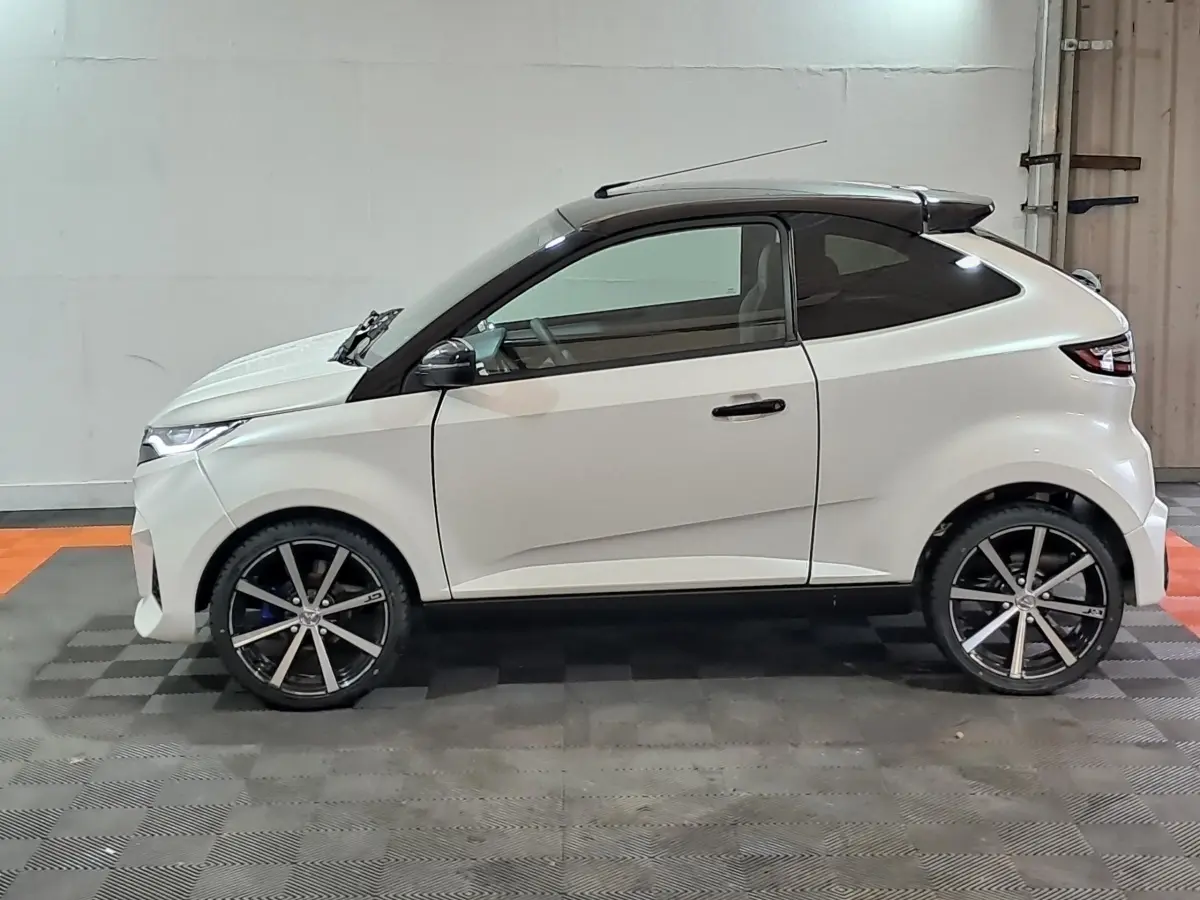 Profil droit de l'AIXAM AMBITION 0.5 CITY COUPE GTI blanc, avec jantes noires et toit noir contrasté.