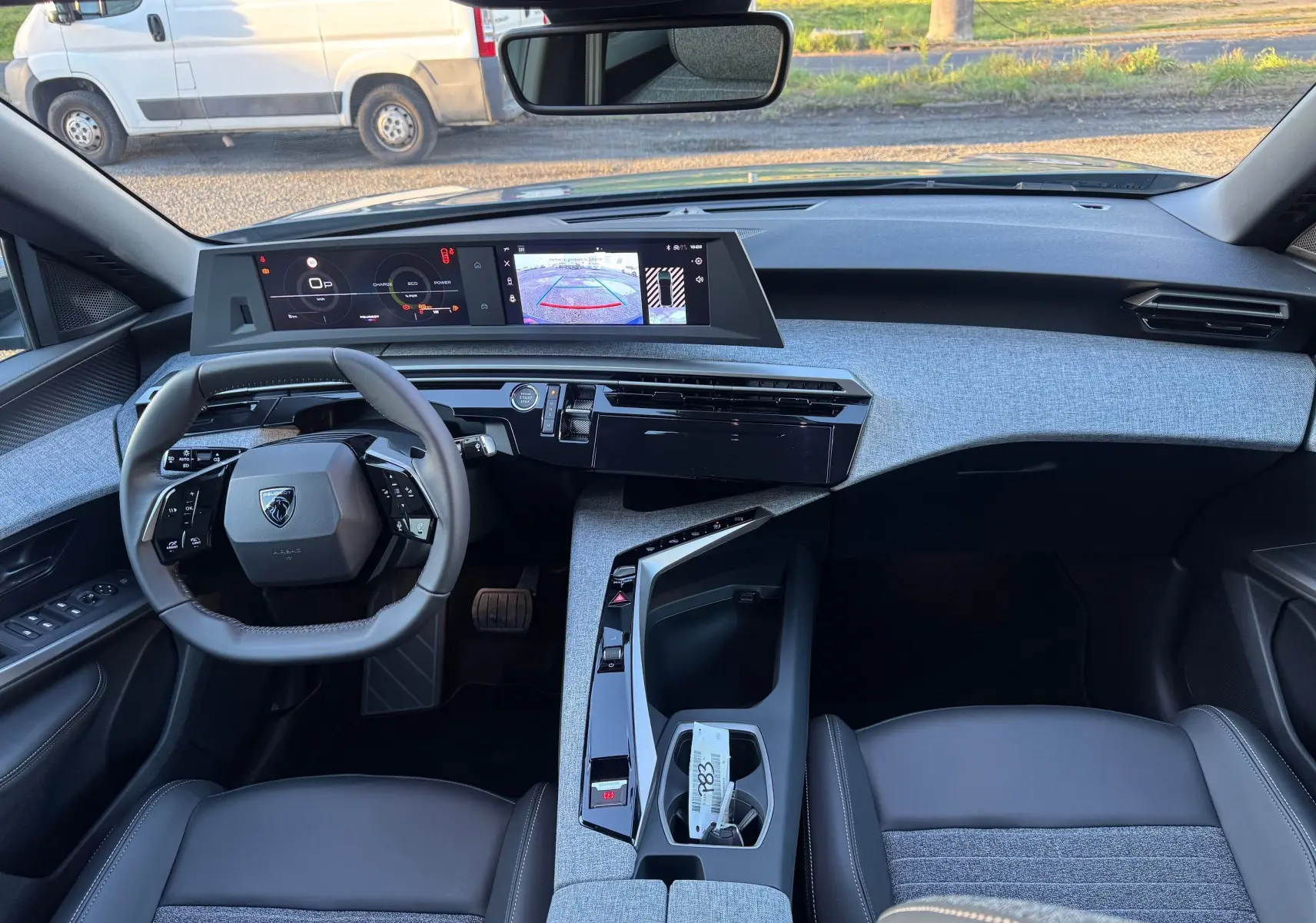 Vue intérieure avant du Peugeot 3008 Hybrid 136ch Allure 2025, tableau de bord moderne avec écran numérique et volant compact gris noir.