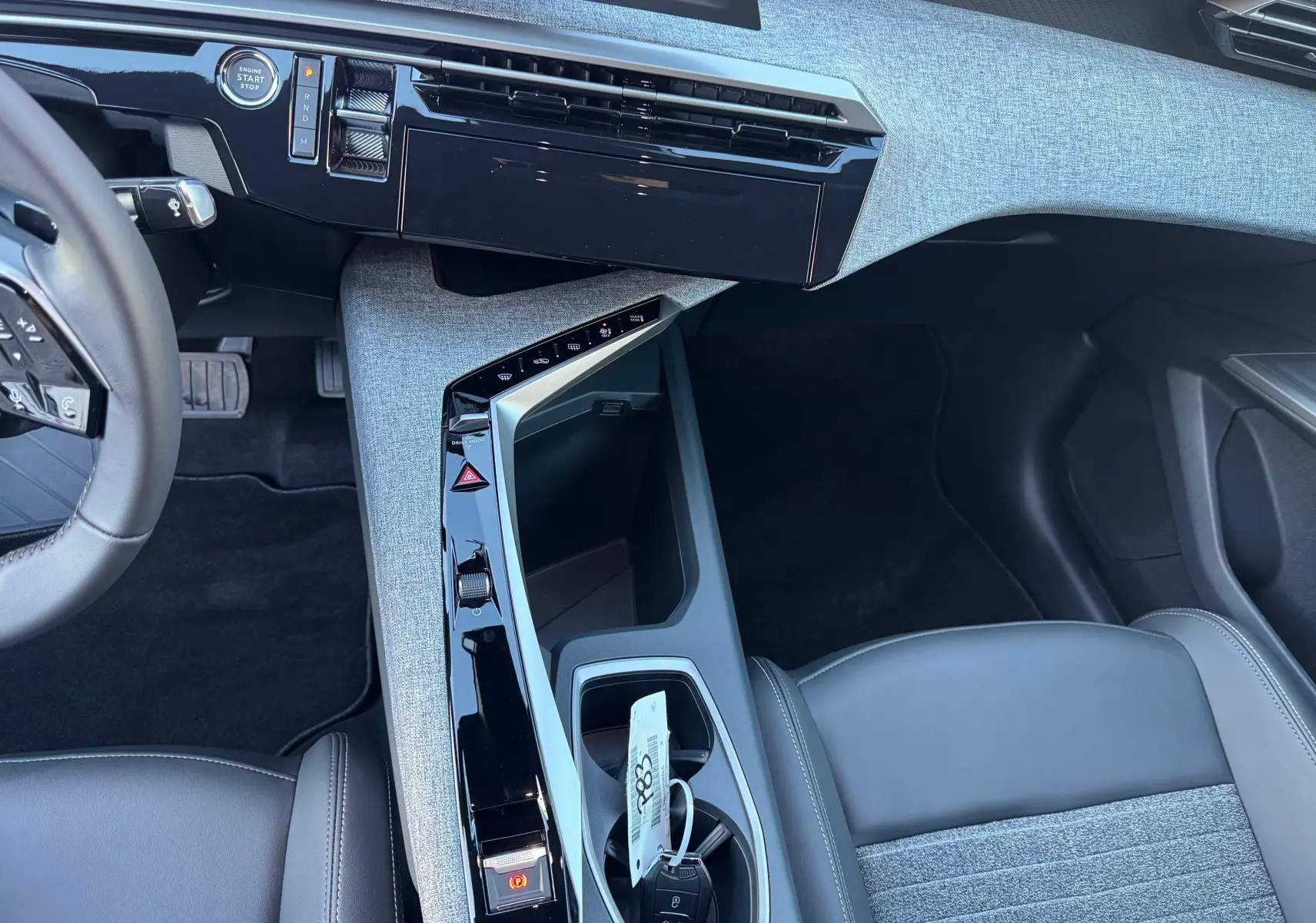 Vue intérieure centrée sur la console centrale et siège avant droit gris noir du Peugeot 3008 Hybrid 2025.