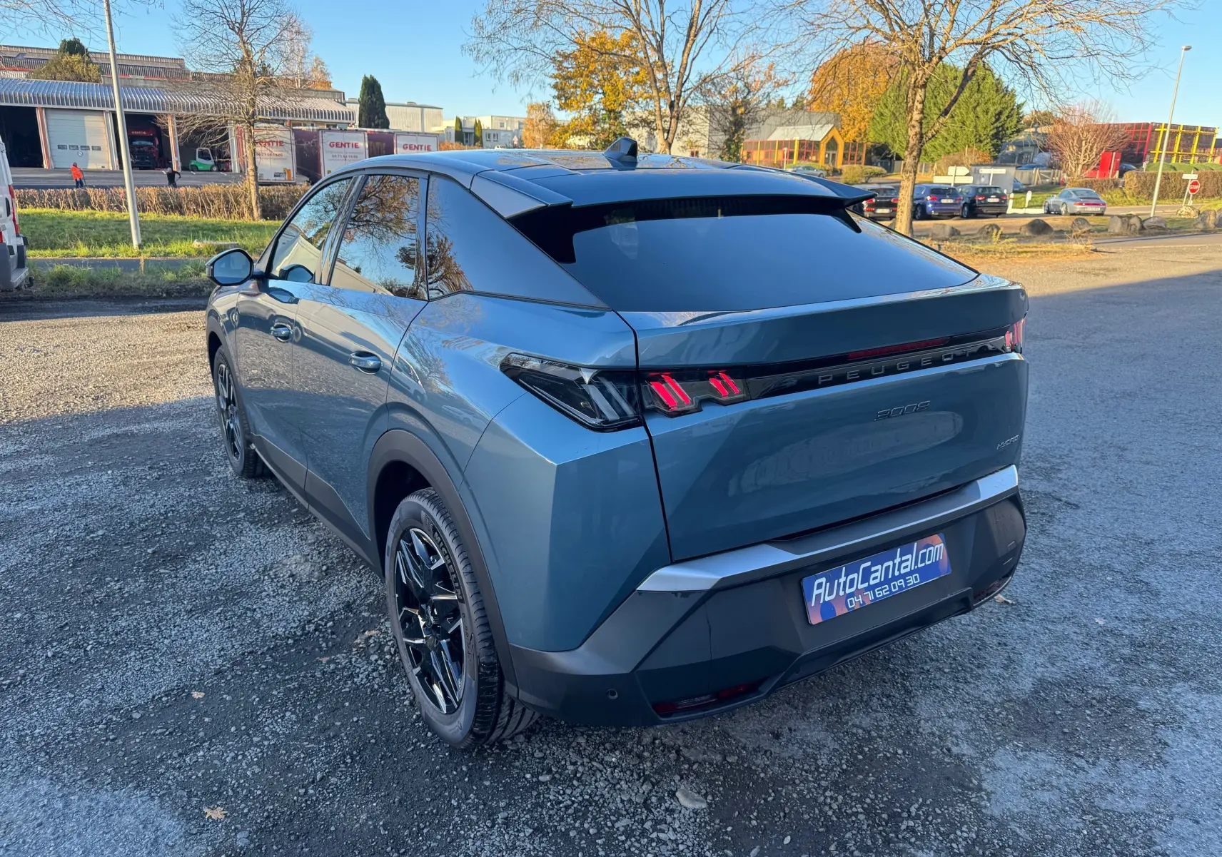 Vue 3/4 arrière droite du Peugeot 3008 Hybrid bleu Nogaro avec feux arrière LED distinctifs et toit noir brillant.