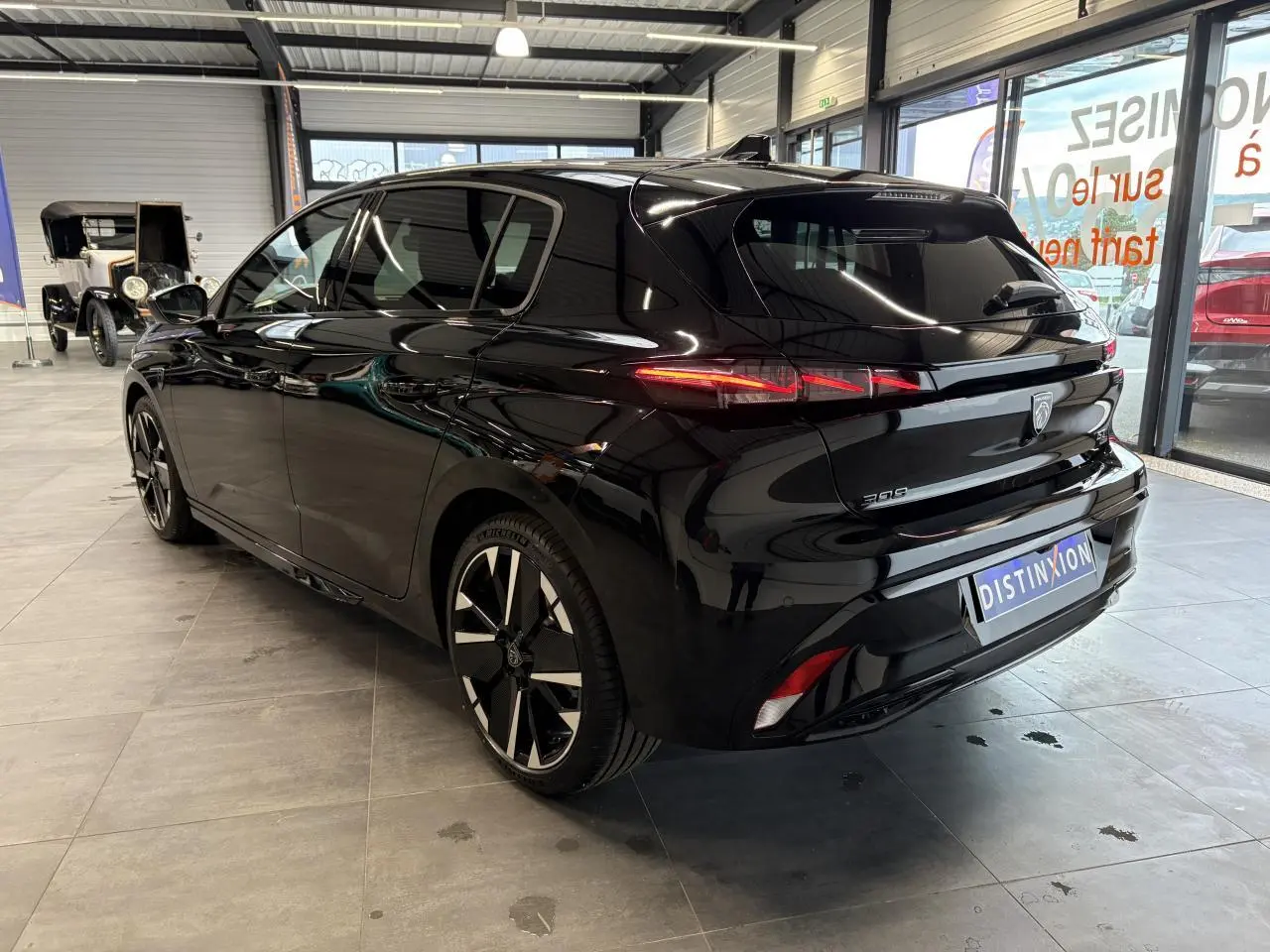 Vue 3/4 arrière droite d'une Peugeot 308 GT noire métallisée avec jantes alliage bi-tons et feux arrière LED distinctifs.