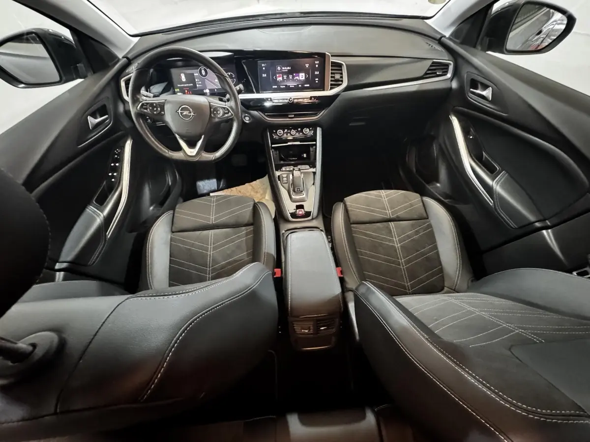 Vue intérieure avant de l’Opel Grandland 2022, sièges noirs, volant cuir multifonctions et écran tactile central.