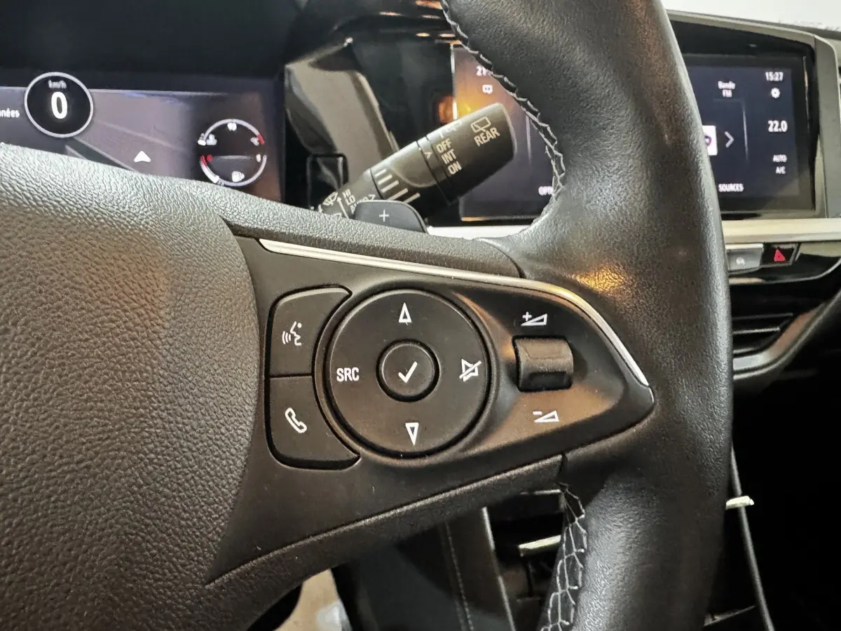 Gros plan sur le volant cuir noir d’un Opel Grandland 2022, avec commandes multifonctions et écran tactile en arrière-plan.