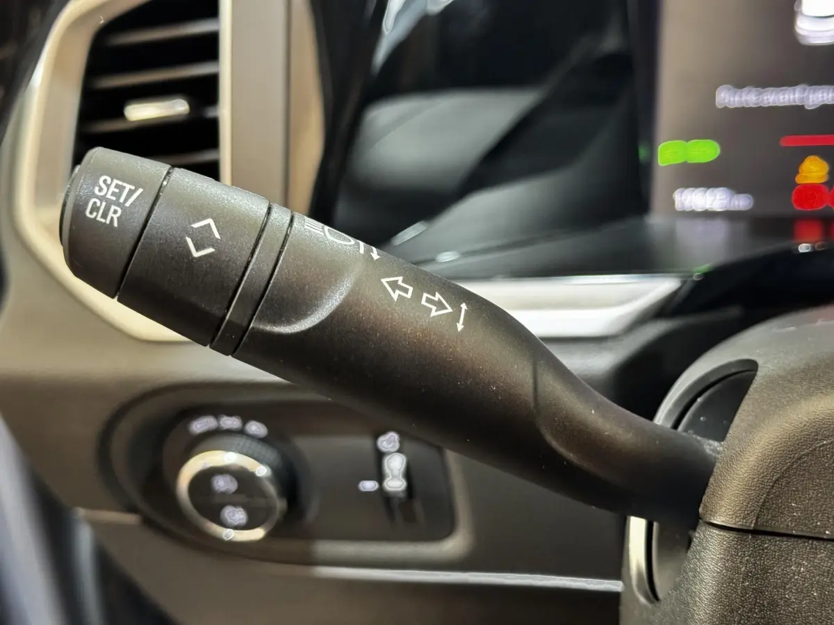 Gros plan sur la manette de clignotant et commandes au volant d'un Opel Grandland gris clair, intérieur moderne.