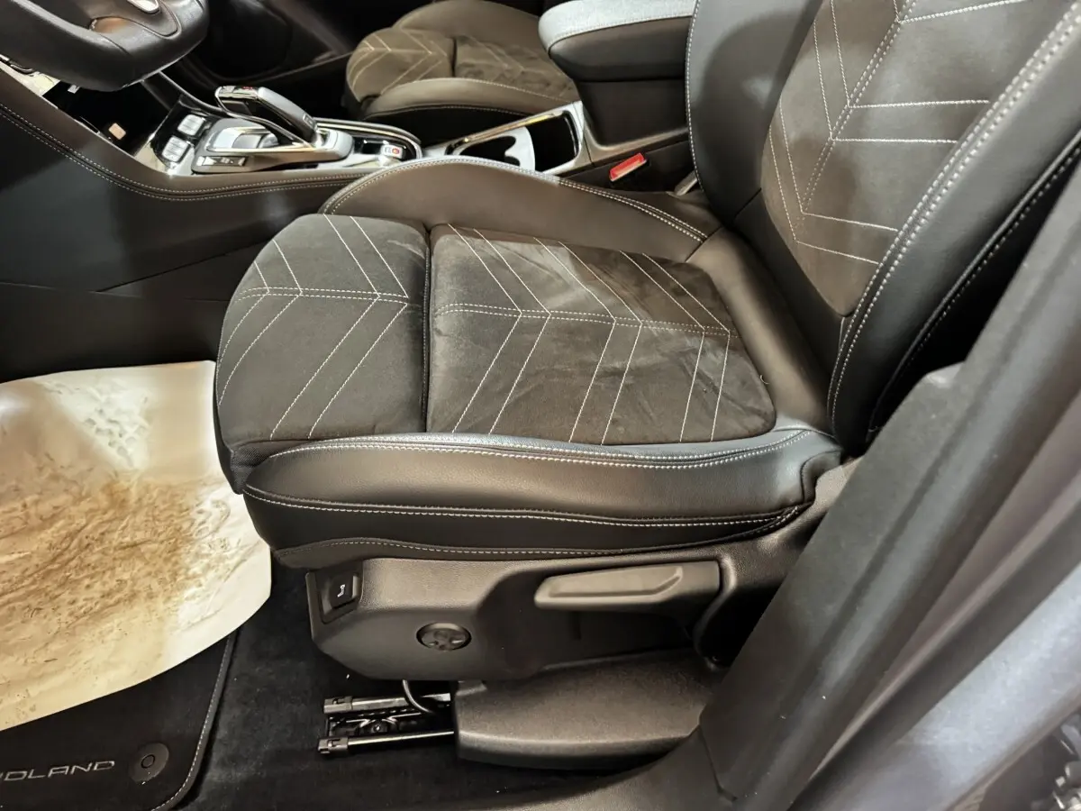 Gros plan sur le siège avant droit en cuir et alcantara noir avec surpiqûres blanches de l’Opel Grandland gris clair.