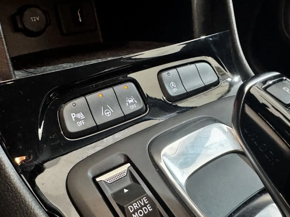 Gros plan sur la console centrale noire avec boutons d’aide à la conduite et levier de vitesse automatique.