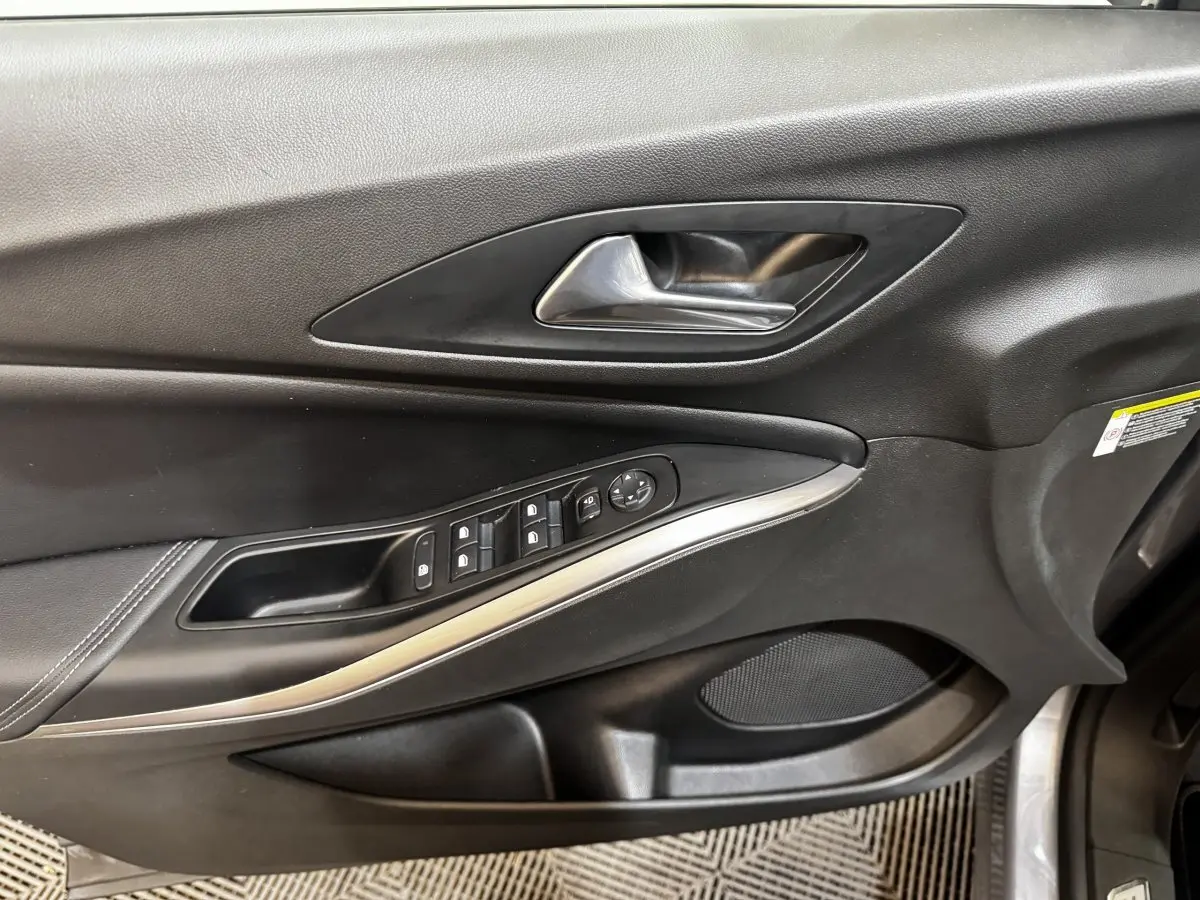 Gros plan sur la porte avant gauche noire de l'Opel Grandland 2022 avec commandes de vitres et poignée métal.