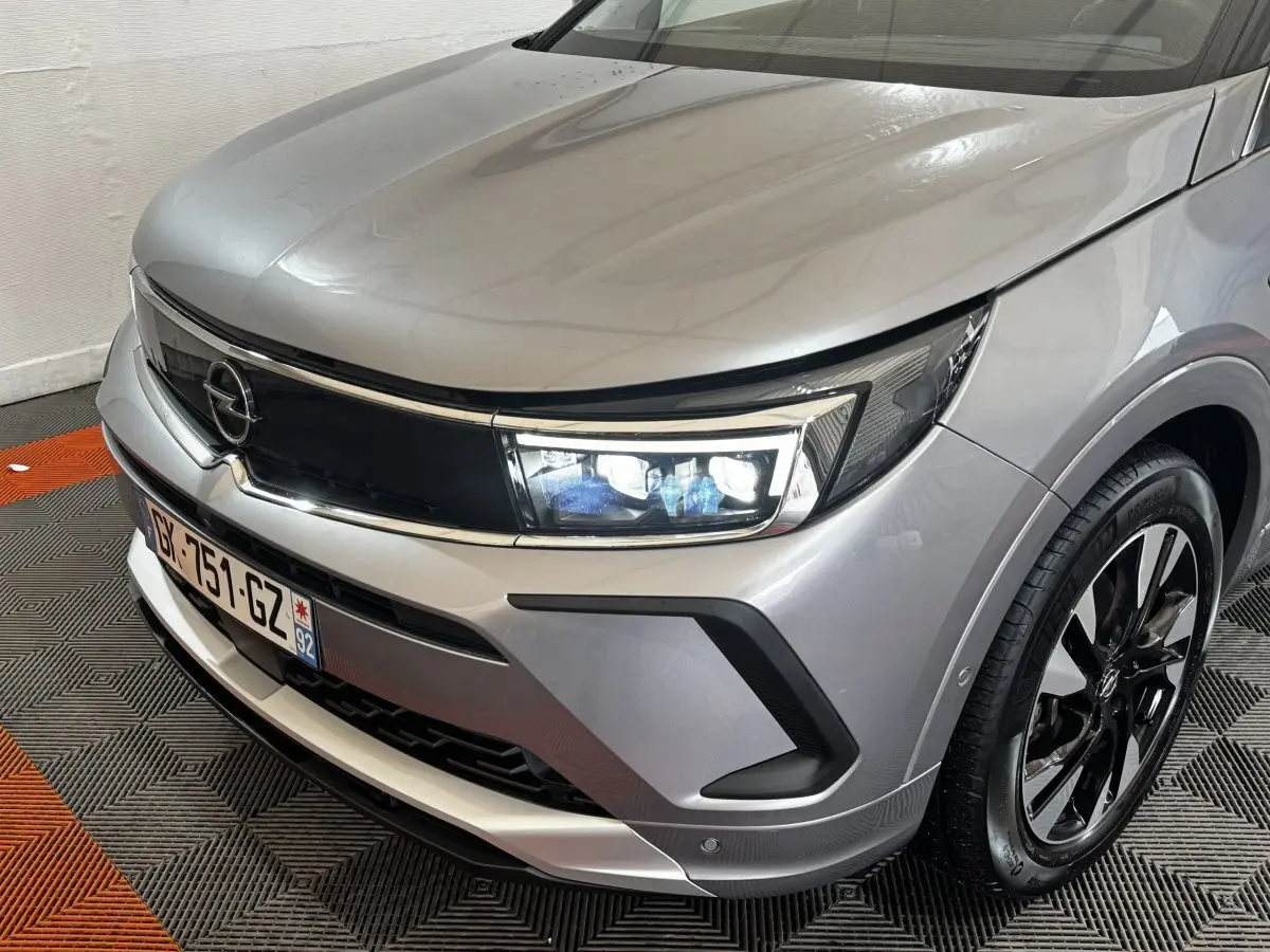 Vue 3/4 avant droit d'un Opel Grandland gris clair avec phares LED et jantes alliage noires.