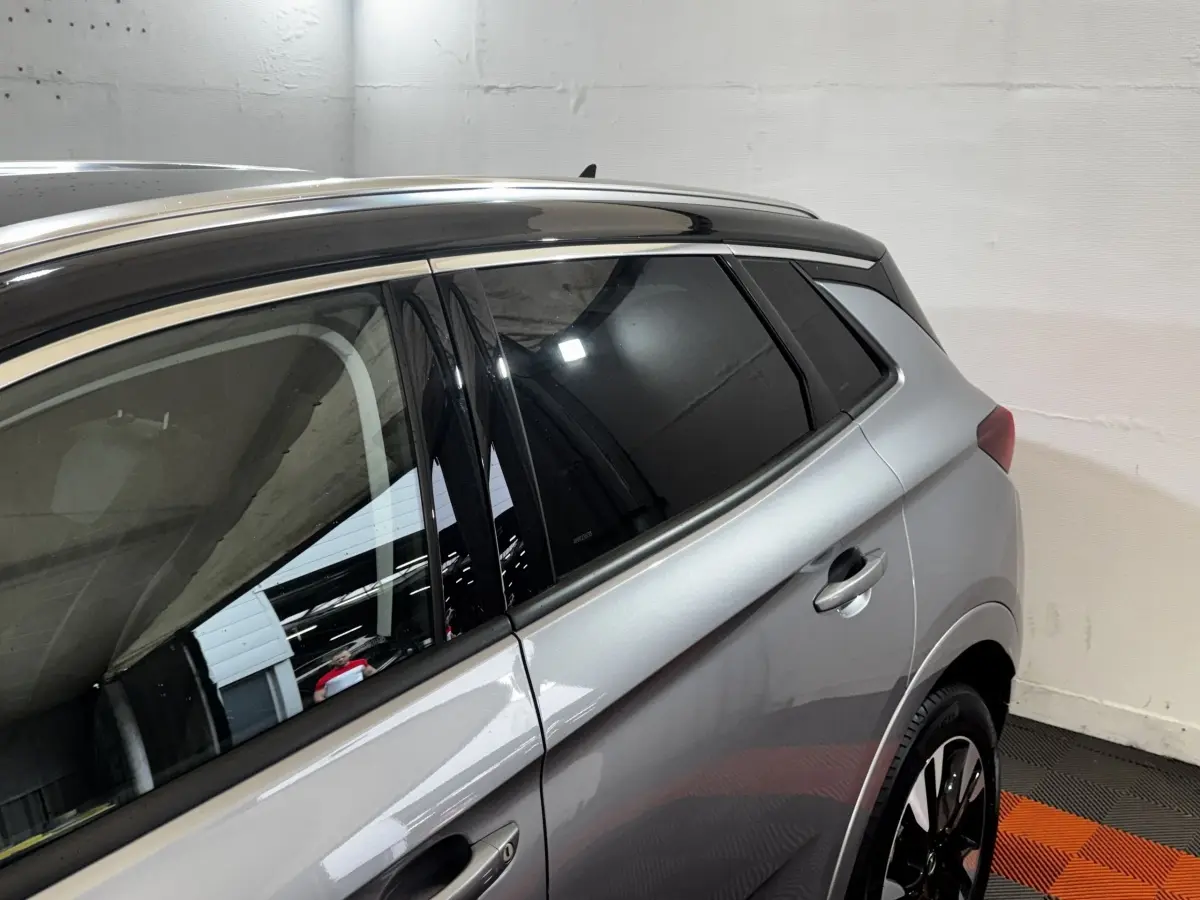Vue latérale droite d’un Opel Grandland gris clair avec toit noir et jantes noires en intérieur.
