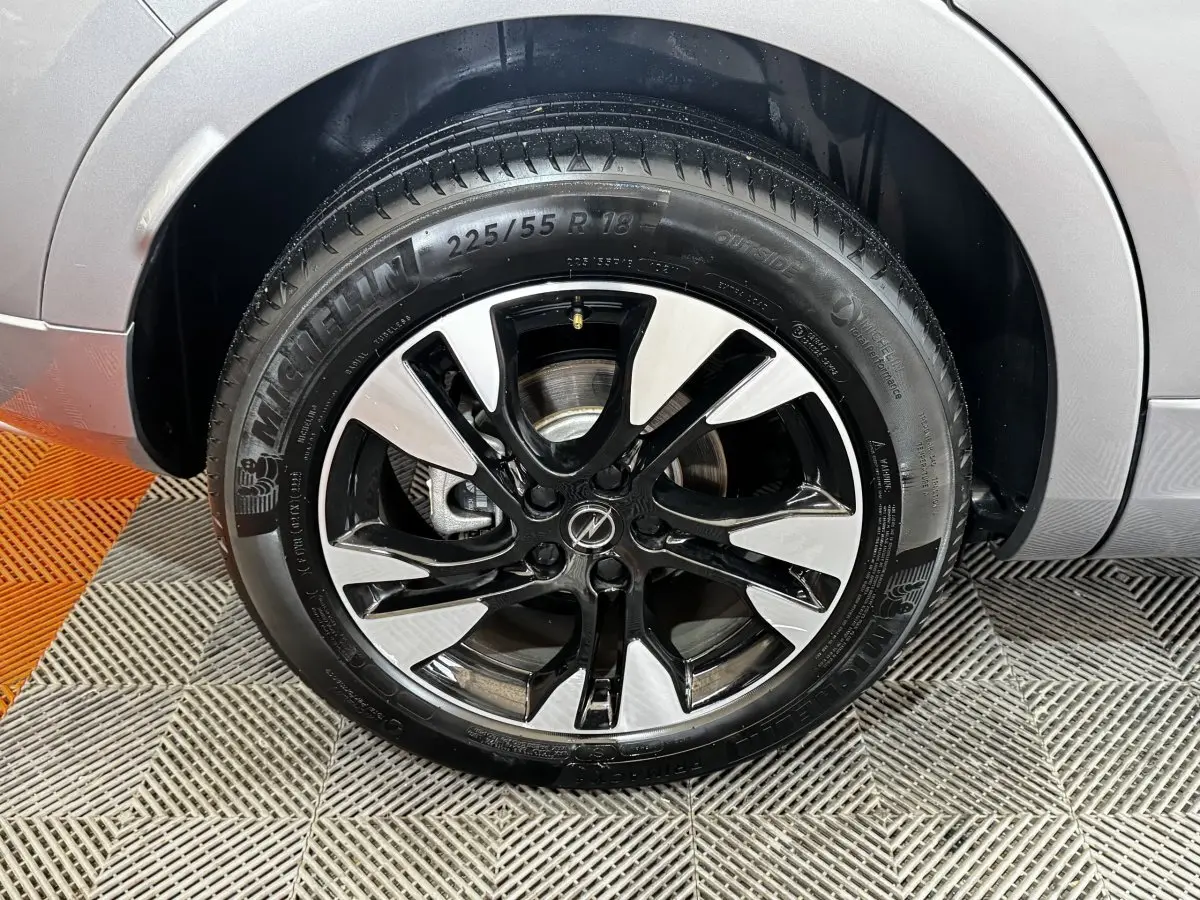 Gros plan sur la roue avant droite d’un Opel Grandland gris clair, jante alliage bicolore et pneu Michelin.