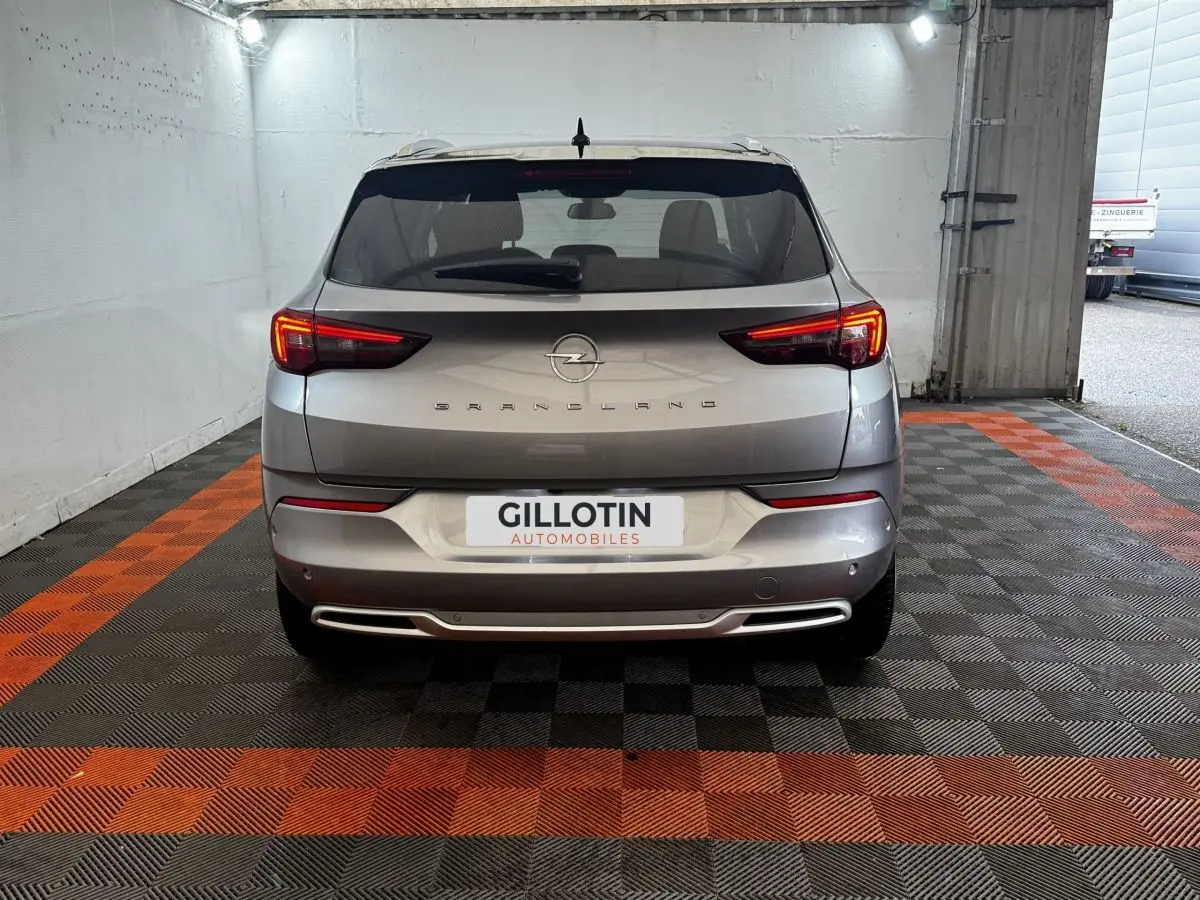 Vue arrière d’un Opel Grandland gris clair 2022 avec feux LED allumés dans un garage.