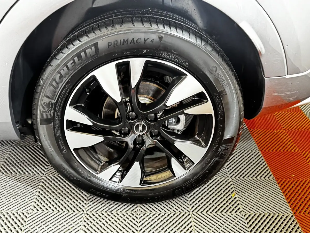 Gros plan sur la roue avant droite d’un Opel Grandland gris clair avec jante alliage bicolore et pneu Michelin.