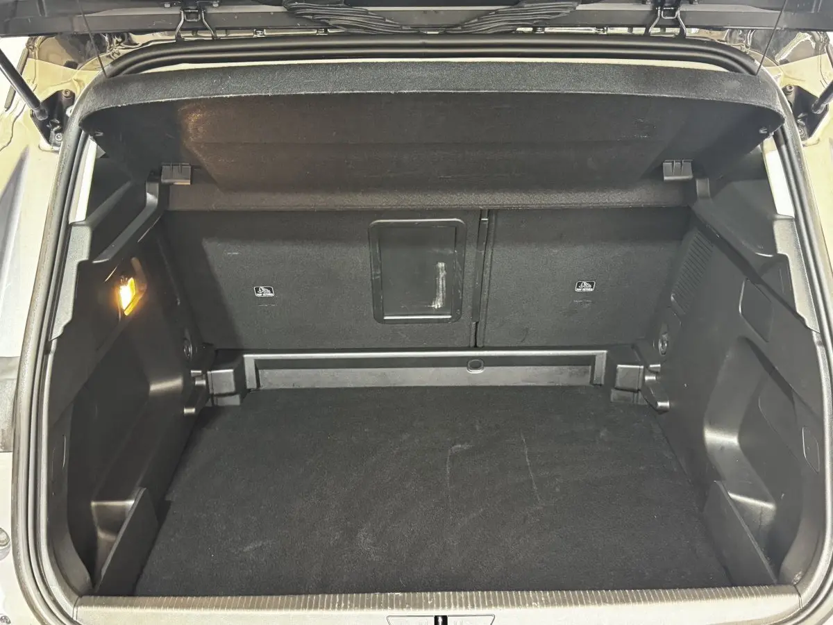 Coffre ouvert vu de l'arrière d'un Opel Grandland gris clair, montrant l'espace de chargement et banquette rabattable.