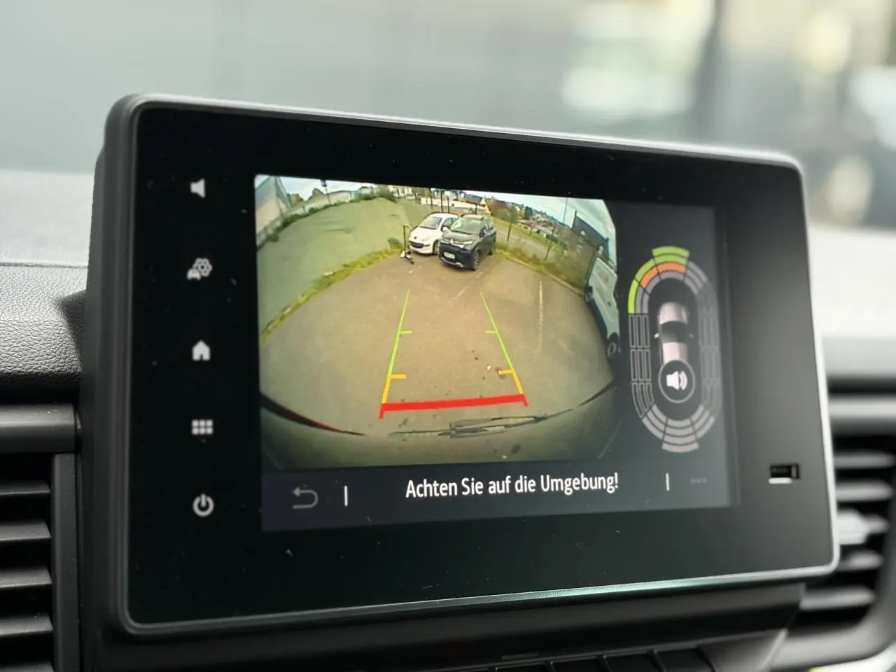 Écran tactile intérieur montrant la caméra de recul du Nissan Primastar Combi noir métal en stationnement.