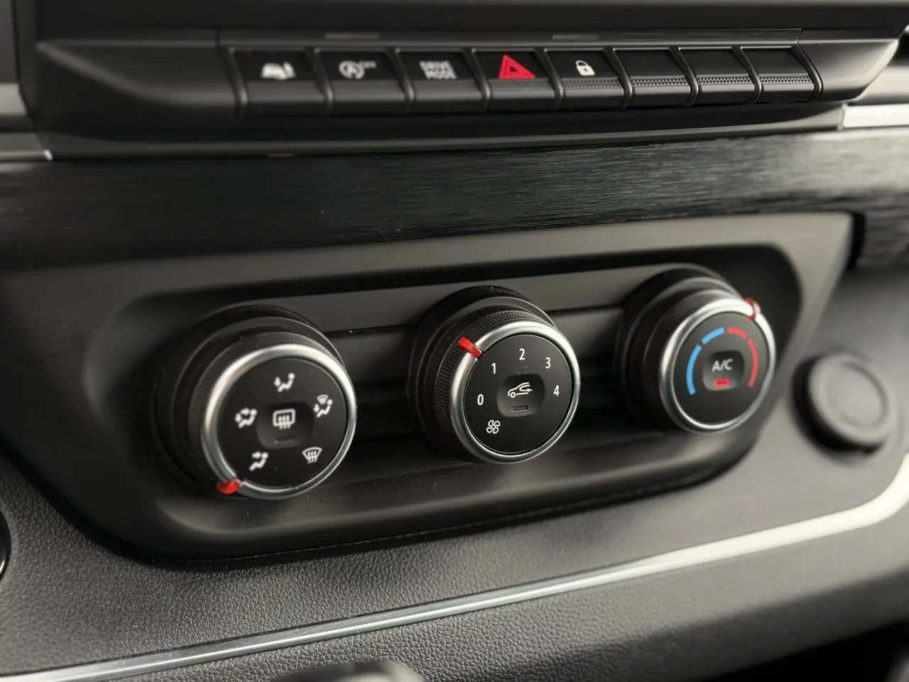 Gros plan sur les commandes de climatisation du Nissan Primastar Combi 2025, boutons noirs avec réglages ventilation et air conditionné.