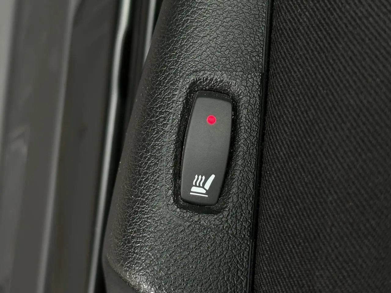 Bouton allumé de siège chauffant sur panneau intérieur noir du Nissan Primastar Combi L2 2025.